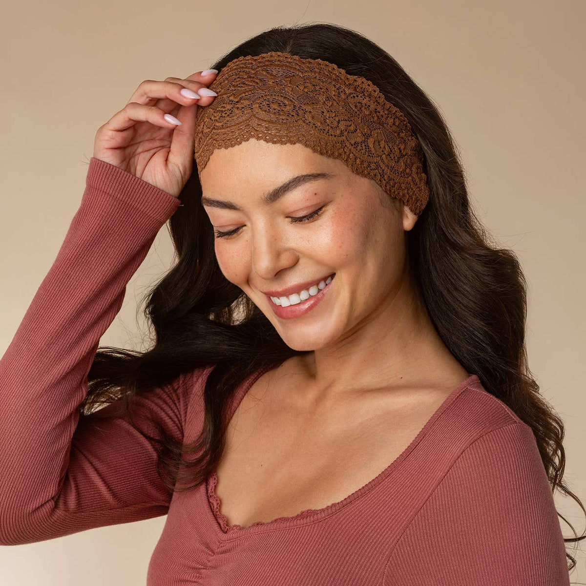 A woman wearing a brown lace elastic wide headband hair accessory and a dusty rose ribbed long-sleeve top